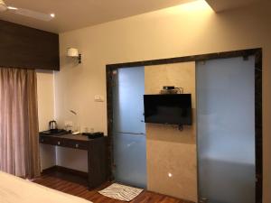 a room with a bed and a desk and a television at Hotel Sharanam in Shegaon