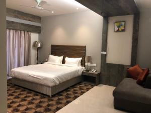 a bedroom with a large bed and a couch at Hotel Sharanam in Shegaon
