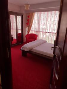 a small bedroom with a bed and a red chair at Pensiunea Ghiocela in Motru