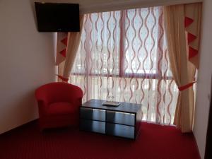 een kamer met een rode stoel, een tafel en een raam bij Pensiunea Ghiocela in Motru