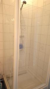 een douche met een glazen deur in de badkamer bij La Caravelle 10 Boulevard Gilbert Longuet in Arromanches-les-Bains