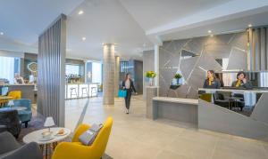 a lobby of a hotel with people sitting at a counter at Maldron Hotel Belfast City in Belfast