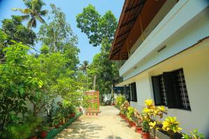 a walkway outside a building with plants and trees at Marari Coastal Dreams Home Stay in Alleppey