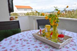 a tray with glasses and a vase with flowers on a table at Holiday Apartment Ivan in Murter +16 photos
