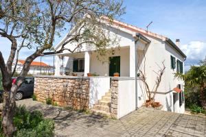 a white house with a stone wall at Holiday Apartment Ivan in Murter