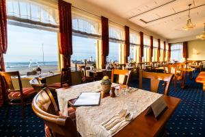 ein Restaurant mit Tischen und Stühlen mit Blick auf das Meer in der Unterkunft Strandhotel Ostfriesenhof in Borkum
