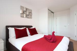 um quarto com uma cama grande e almofadas vermelhas em Luxury Apartments With Secure Parking em Reading