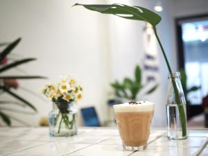 a table with a drink and a vase of flowers at Bangkok Sanookdee Hostel in Bangkok