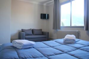 Habitación con cama, sofá y ventana en Le Petit Majestic, en Lourdes