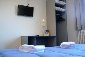 ルルドにあるLe Petit Majesticのテレビ付きの客室で、青いベッド2台が備わります。