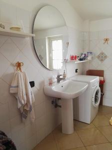 La salle de bains blanche est pourvue d'un lavabo et d'un miroir. dans l'établissement Sellia apartment, à Marina di Sellia