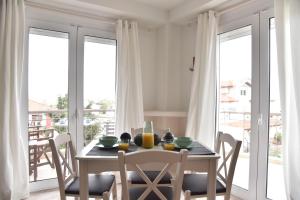 una sala da pranzo con tavolo, sedie e finestre di KyMa Studios and Suites a Asprovalta