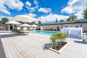 una piscina con sombrillas y una terraza de madera en Katrinelund Gästgiveri & Sjökrog, en Stora Mellösa