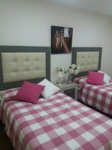 2 letti in una camera da letto con lenzuola viola e bianche di Apartamento el Torreón a Setenil