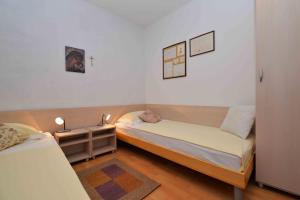 a small bedroom with two beds and a night stand at Holiday Apartment Ivan in Murter