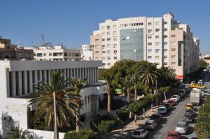 una strada di città con auto parcheggiate di fronte agli edifici di Hotel El Layeli a Sfax