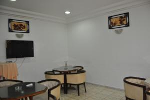 a waiting room with a tv and tables and chairs at Hotel El Layeli in Sfax