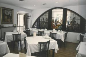 un comedor con mesas y sillas blancas y una ventana en La Casona de Jovellanos, en Gijón