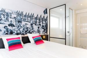 a bedroom with a large white bed with two colorful pillows at Hotel Nelson in Knokke-Heist