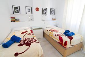 2 łóżka pojedyncze w pokoju z obrazami na ścianie w obiekcie ALBAIDA II 6i MENYBER w mieście Nerja +8 zdjęć
