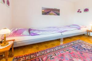 a bed in a room with a table and a rug at Privatzimmer Ulbricht/Föhr in Friedrichshafen