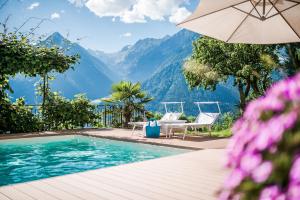 una piscina con sombrilla, sillas y montañas en Haus Artus, en Scena