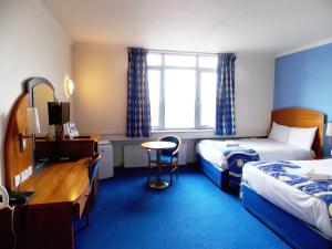 a bedroom with a bed, desk, chair and a television at London - Wembley International Hotel in London