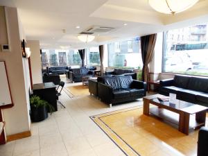 a living room with couches and tables and windows at London - Wembley International Hotel in London