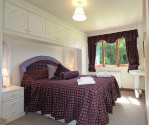 a bedroom with a bed with a purple bedspread at Cysgod y Coed in Dolgellau