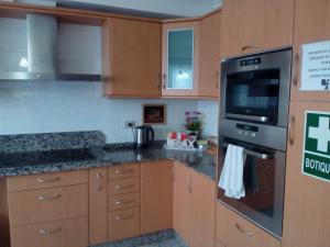 a kitchen with wooden cabinets and a stove top oven at Albergue Aqua Portomarin in Portomarin