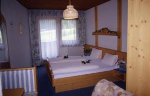 Un dormitorio con una gran cama blanca con flores. en Hotel-Gasthof Waldcafé, en Neustift im Stubaital