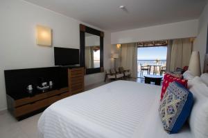 a bedroom with a bed and a television and a balcony at Grand Decameron Los Cabos, A Trademark All-Inclusive Resort in San José del Cabo