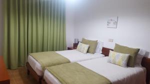 two beds in a hotel room with green curtains at Mira Parque in Albufeira