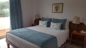 a bedroom with a bed with blue pillows and a window at Mira Parque in Albufeira