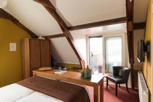 Schlafzimmer mit einem Bett, einem Schreibtisch und einem Fenster in der Unterkunft Hotel Restaurant It posthus in Birdaard