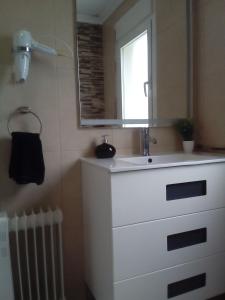 een badkamer met een witte wastafel en een spiegel bij Albergue Aqua Portomarin in Portomarin