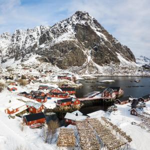 a village covered in snow with a mountain in the background at Å Rorbuer - by Classic Norway Hotels in Å