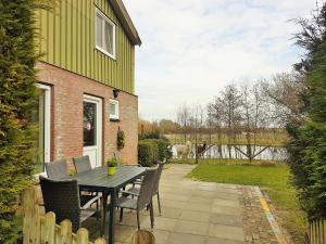 a patio with a table and chairs next to a house at Aan de Waterspiegel in Aagtekerke