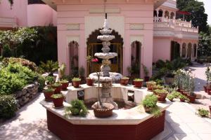贾朗达尔Savrupson Heritage Home的粉红色建筑前有一个喷泉，周围摆放着盆栽植物。
