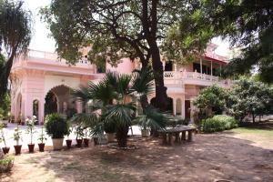 贾朗达尔Savrupson Heritage Home的一座粉红色的建筑,前面有棵树和长凳