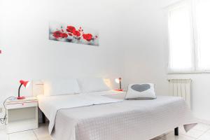 a white bedroom with a bed with a heart pillow on it at Casa Vacanze Cau in Alghero