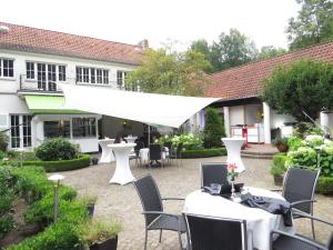 eine Terrasse mit weißen Tischen und Stühlen und ein Gebäude in der Unterkunft Gästehaus Villa Wolff in Bomlitz