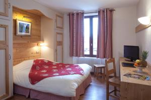 a bedroom with a bed and a desk with a television at Grand Hotel de Valloire et du Galibier in Valloire +34 photos