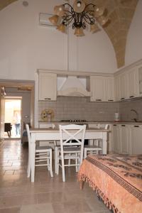 cocina con armarios blancos, mesa y sillas en Casa Jacqueline al borgo, en Giuliano