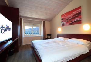 um quarto com uma cama grande e uma televisão de ecrã plano em New Elvezia em Ascona