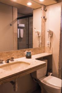 a bathroom with a sink, toilet and mirror at Oft Tamandaré Plaza Hotel in Goiânia