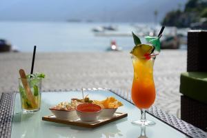 einen Tisch mit einem Getränk und einem Teller Essen am Strand in der Unterkunft New Elvezia in Ascona