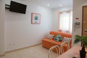 Il comprend un salon doté d'un canapé orange et d'une télévision à écran plat. dans l'établissement Casa Assunção, à Sesimbra