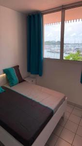 a small bedroom with a bed with a window at Marin'a baie Martinique in Le Marin