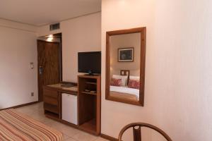 a living room with a television and a dresser at Oft Tamandaré Plaza Hotel in Goiânia